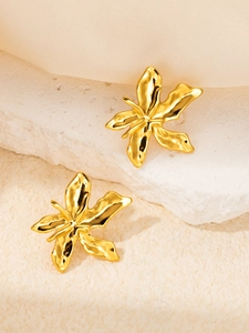 Macro shot of gold flower petal earrings with textured metal finish on stone background