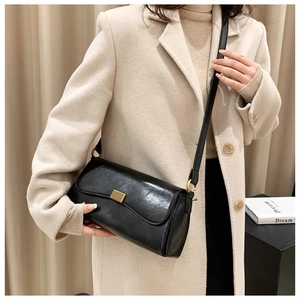 Elegante schwarze Leder-Schultertasche mit Goldschloss am beigen Outfit präsentiert