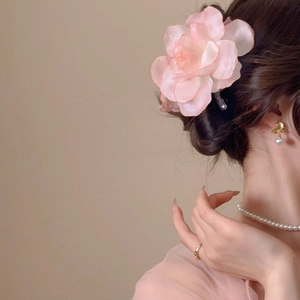 Detail of pink fabric flower hair clip on model with elegant jewelry set