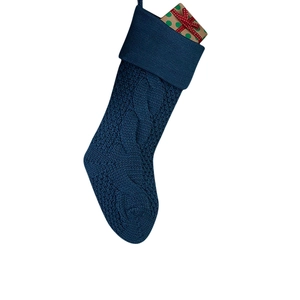 Detail of dark blue cable knit Christmas stocking with a wrapped gift box inside