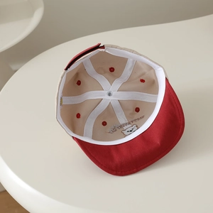 Détail de l'intérieur d'une casquette bébé avec coutures renforcées et broderie ours