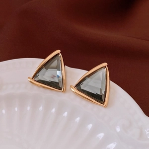 Macro view of triangular gold-framed earrings with smoky grey crystal insets