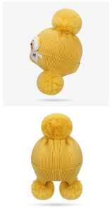 Detailed knit texture of a yellow winter hat with three plush pompoms for toddlers