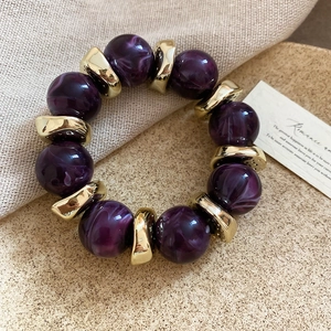 Detail of purple marble acrylic beads and golden metal spacers on a chic beaded bracelet