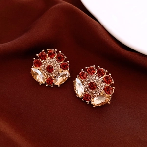 Detailed close-up of vintage floral earrings with red and champagne crystals on gold base