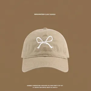 Detailed close-up of khaki sun hat featuring white butterfly embroidery and premium cotton fabric