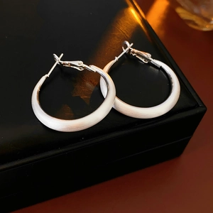 Close-up of matte silver geometric hoop earrings placed on a black jewelry box