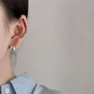Close-up of minimalist S925 sterling silver ball stud earrings and sleek ear cuff