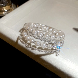 Macro detail of multi-layer pearl bracelet with sparkling rhinestone ring on jewelry tray