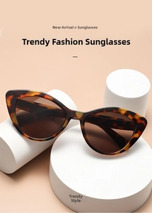 Detailed view of tortoiseshell cat-eye sunglasses with dark lenses on white props