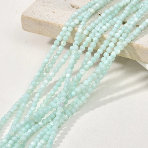 Macro view of 3mm light blue natural freshwater shell beads on a textured stone