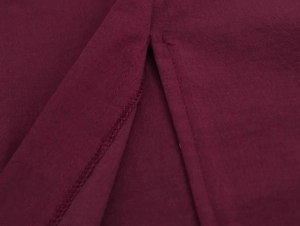 Detail of burgundy straight trousers showing high-quality stitching and fabric texture