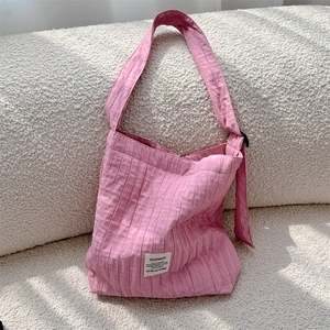 Detail of pink pleated canvas crossbody bag with white woven label on soft texture