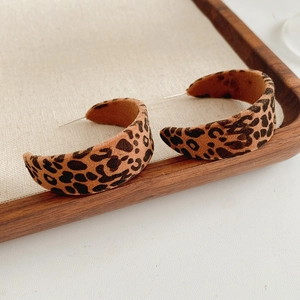 Close-up of leopard print velvet hoop earrings on a wooden tray with linen padding