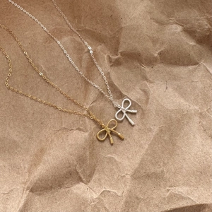 Detailed view of gold and silver bow necklaces with rope texture on kraft paper