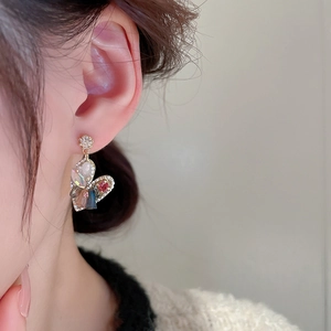 Close-up of heart-shaped crystal earrings with gold plating on a model's ear