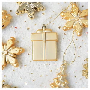 Flat lay of gold metallic Christmas ornaments featuring gift box and snowflake shapes
