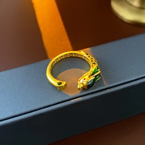 Detailed close-up of golden dragon-shaped ring with green and blue enamel on jewelry box