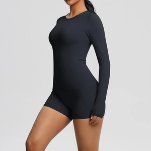 Détail du haut de yoga noir à manches longues et du short de sport taille haute sur modèle