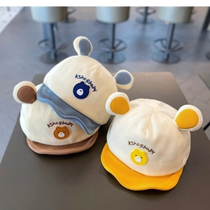 Détail de casquettes bébé en velours côtelé bleu, marron et jaune avec oreilles d'ours