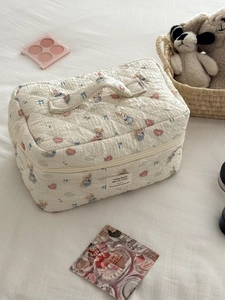 Detailed close-up of quilted cosmetic bag with cute rabbit and heart prints on white fabric