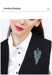 Peacock brooch with blue rhinestones shown on a black suit vest over a white shirt