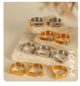 Detail of gold and silver open rings with geometric bar and bead on travertine stone
