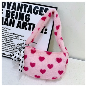 Detail of pink plush shoulder bag with red heart patterns and a polka dot silk ribbon