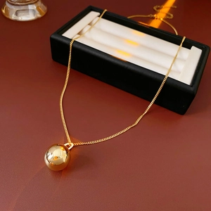 Detail shot of a minimalist gold titanium necklace featuring a spherical metal pendant