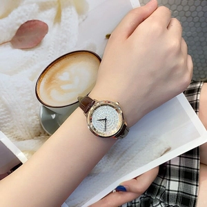 Close-up of rose gold watch with crystal-encrusted dial and brown leather strap on wrist