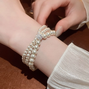 Elegant triple-layer pearl bracelet with zircon clasp on silk fabric background