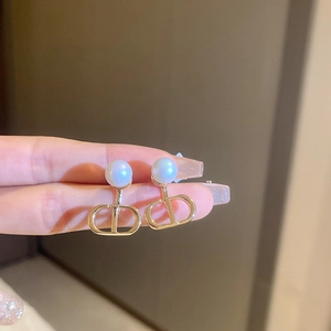 Detail of gold-tone pearl earrings featuring the iconic hollowed CD logo design