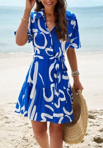 Close-up of blue dress with white abstract letter print, shirt collar, and button details