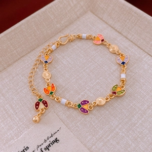 Detailed view of colorful enamel ladybug charms on a gold bracelet in a gift box