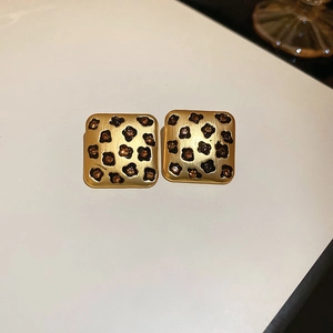 Detail of square gold earrings with leopard print pattern and amber crystal inlays