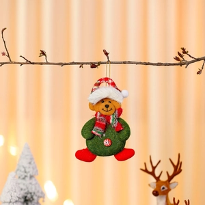 Detail of plush Christmas bear ornament with festive green coat and red scarf on a branch