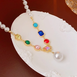Detail of colorful crystal gemstones and pearl necklace on a decorative white plate