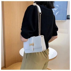 Detailed side view of white crocodile pattern shoulder bag with golden chain and clasp