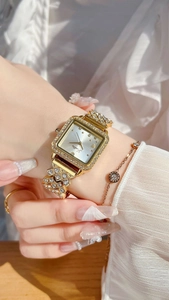 Detail of elegant gold square watch with crystal inlay paired with a matching bracelet