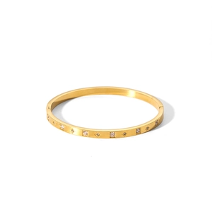 Dettaglio di un bracciale rigido placcato oro 18k con zirconi incastonati su fondo bianco