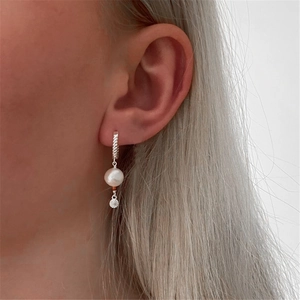 Detail of s925 silver twist star hoop earring with pearl pendant worn by model