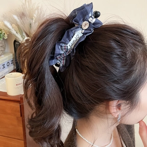 Vue détaillée d'une pince à cheveux à carreaux bleu foncé portée en queue de cheval par un mannequin
