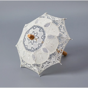 Detail of white bridal lace umbrella featuring intricate floral embroidery and wooden handle