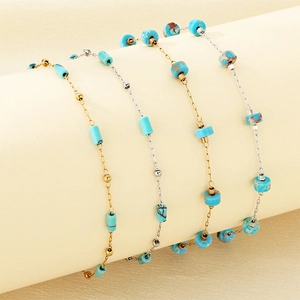 Detailed macro of gold and silver beaded bracelets with turquoise stones on a stand