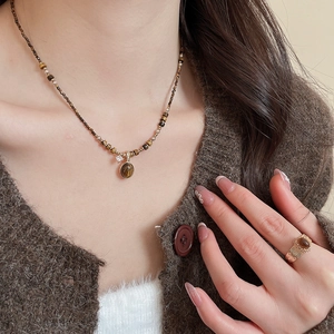 Detail of gold plated tiger eye necklace and ring set worn on a brown cardigan