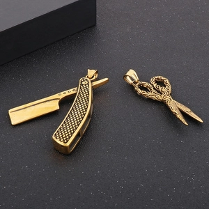 Detailed view of gold vintage razor and ornate scissors pendants on black background