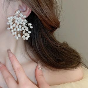 Close-up of elegant flower firework earrings with white pearls and woven gold wire