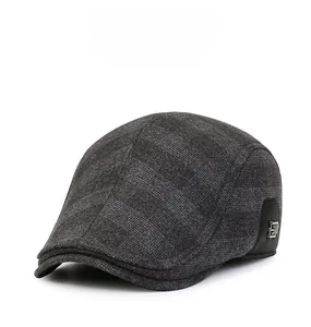Detail of dark grey plaid flat cap with metallic E logo and thick winter fabric