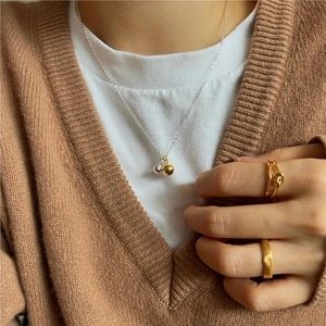 Minimalist 925 sterling silver double bead necklace and textured gold rings on model