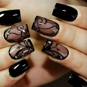 Macro shot of square press-on nails with black swirls and rhinestone embellishments
